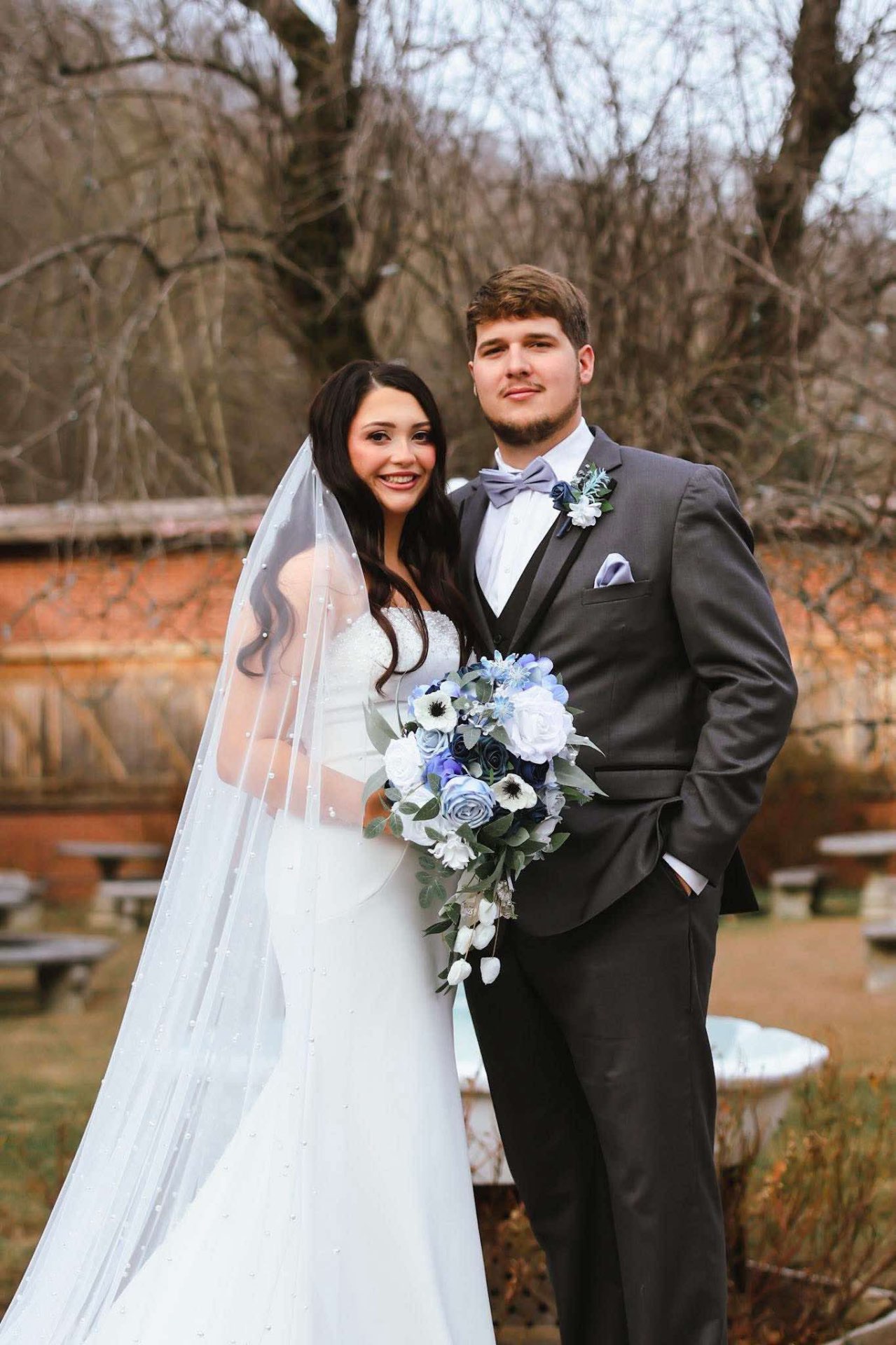 Bride and groom in grey tuxedo with blue bouquet