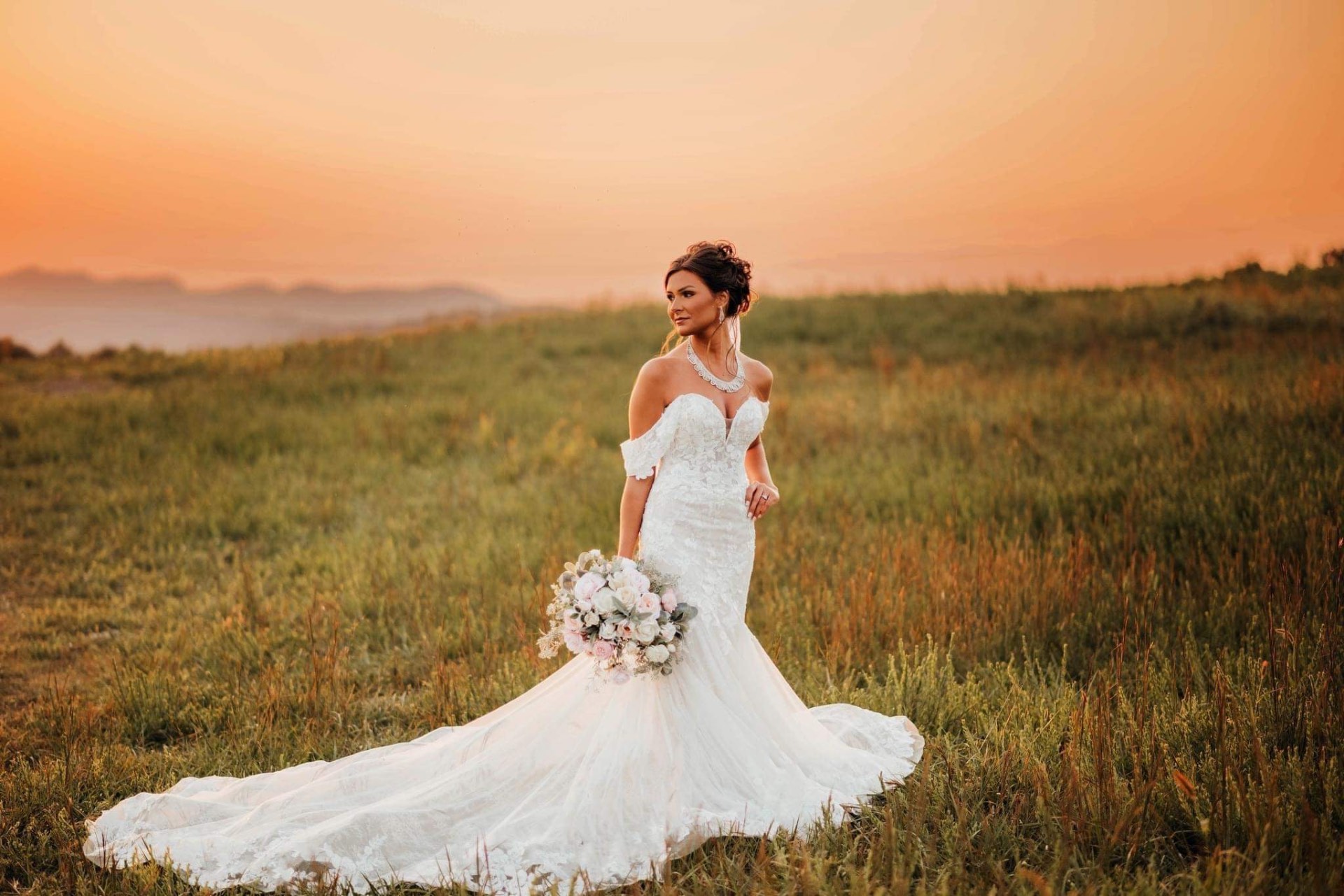 Bride in off-shoulder lace mermaid gown at sunset